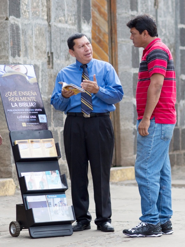 Un testigo de Jehová participando en la predicación pública con un exhibidor de publicaciones