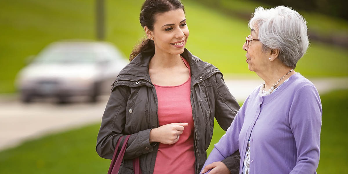 ’n Jong suster hou ’n ouer suster aan haar arm vas.