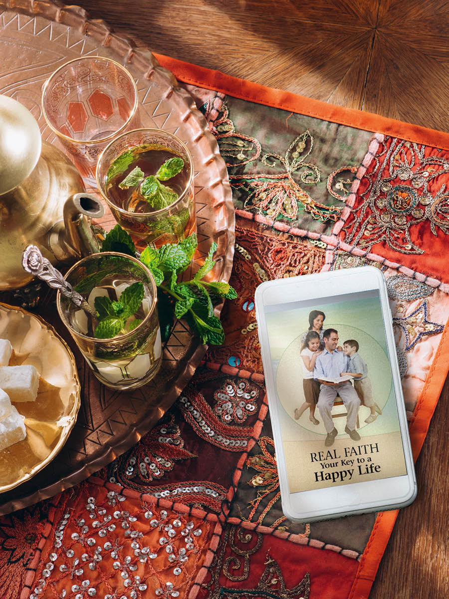 ’n Slimfoon lê langs twee koppies koffie. Die brosjure ‘Real Faith—Your Key to a Happy Life’ word vertoon op ’n slimfoon.