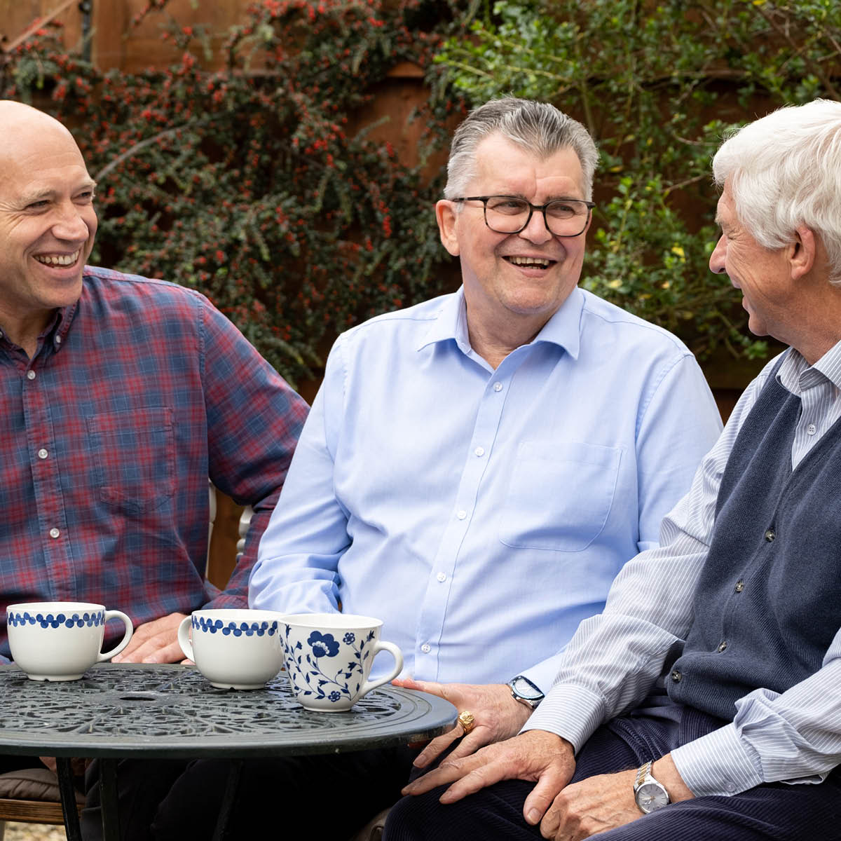 Kevin drink koffie saam met twee vriende.
