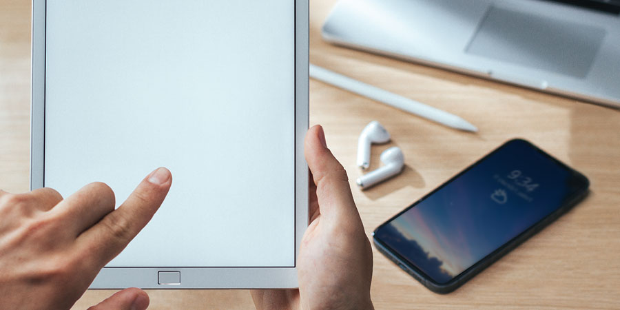 شخص يستعمل جهازًا الكترونيًّا.‏ وهناك اجهزة اخرى على طاولة مجاورة