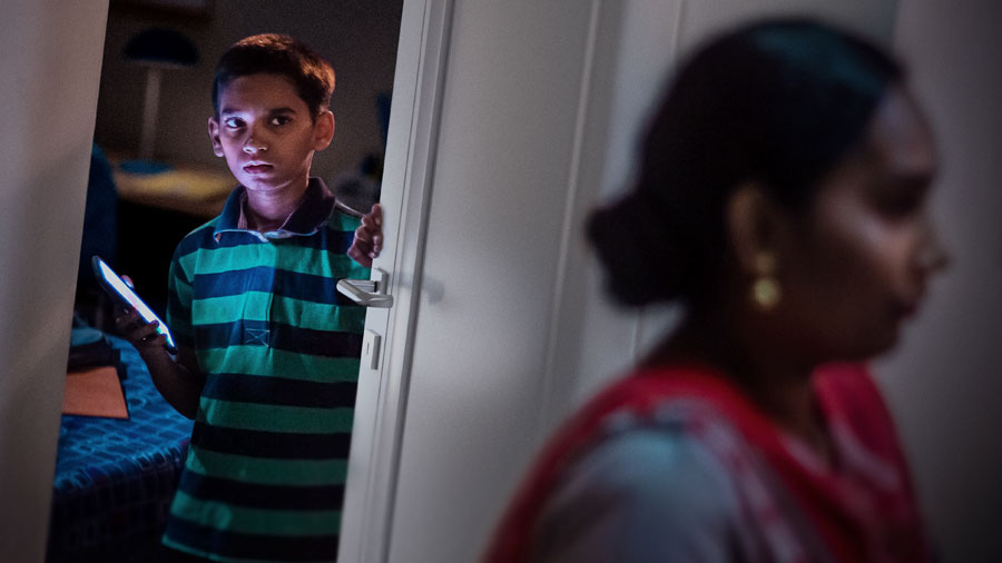 صبي يحمل هاتفًا ذكيًّا ويغلق باب غرفته بعصبية فيما تمر أمه قربه