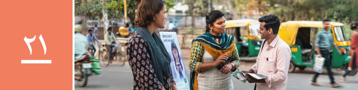 الدرس ٢١:‏ رجل في احدى المدن يتكلم مع شاهدتين ليهوه تقفان قرب عربة المطبوعات