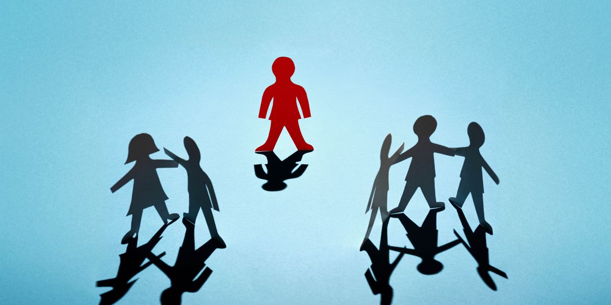 دمية ورقية تقف وحدها بعيدًا عن دمى ورقية أخرى تقف مع غيرها