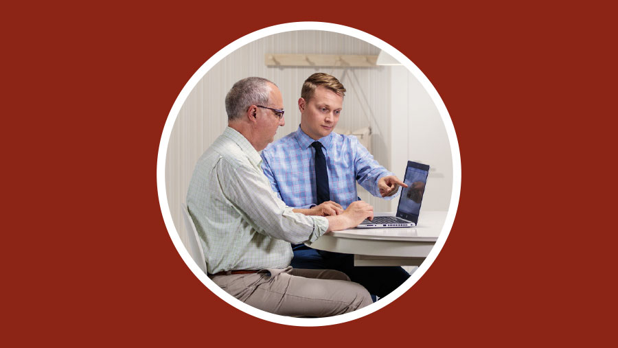 اخ يعلِّم تلميذه كيف يقوم ببحث على جهاز الكتروني.‏