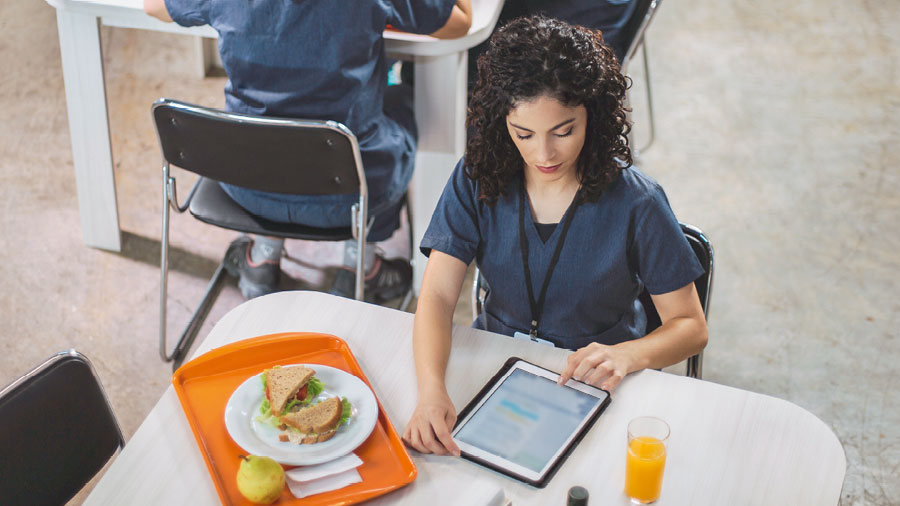 الاخت تستخدم كمبيوترها اللوحي في درسها الشخصي خلال استراحة الغداء في العمل