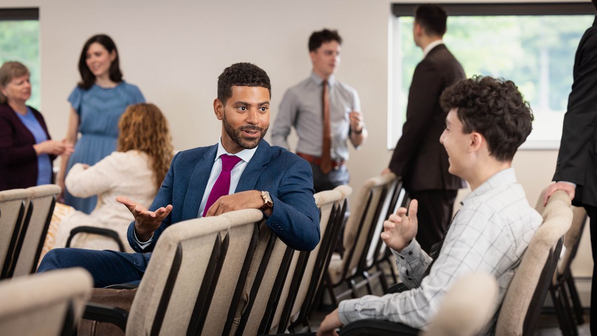 الأخ يجلس مقابل المراهق بعد الاجتماع،‏ وهما يبتسمان ويستمتعان بمحادثة ودِّية