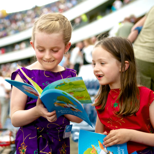 Two young girls looking through the brochure My Bible Lessons at a convention