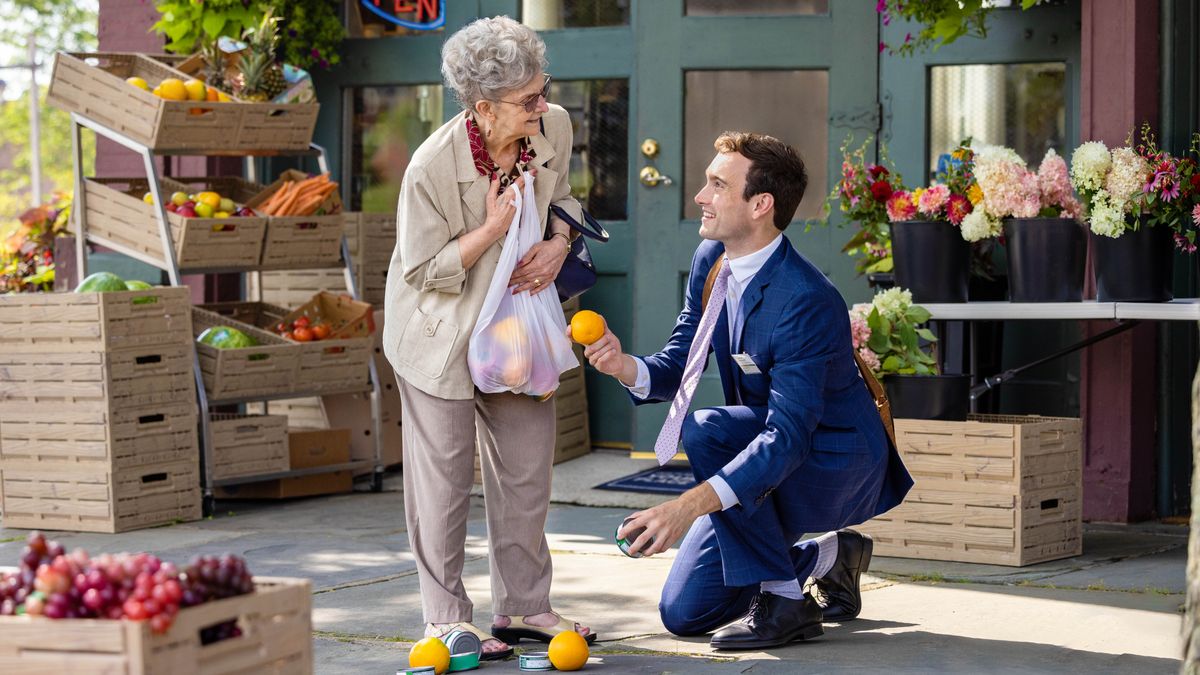 Un frère aide une dame âgée à ramasser des oranges qui sont tombées de son sac de courses.