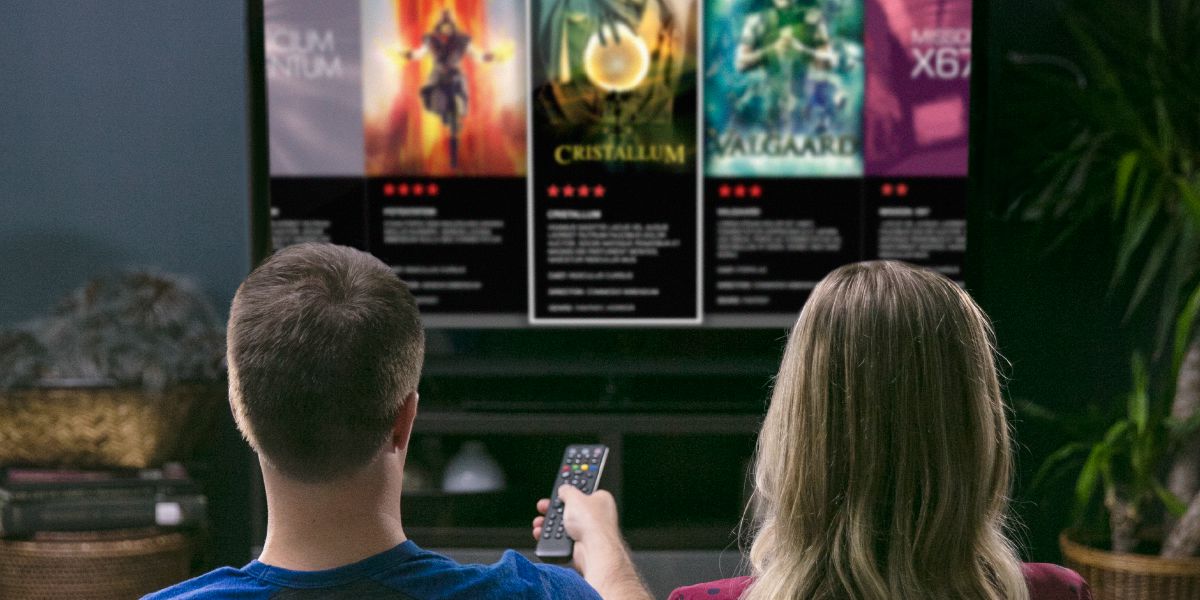 Um casal olha propagandas de filmes de ocultismo na TV