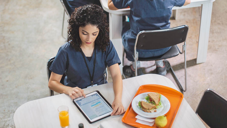 A mesma irmã usa um tablet para estudar a Bíblia durante o intervalo do almoço no serviço.