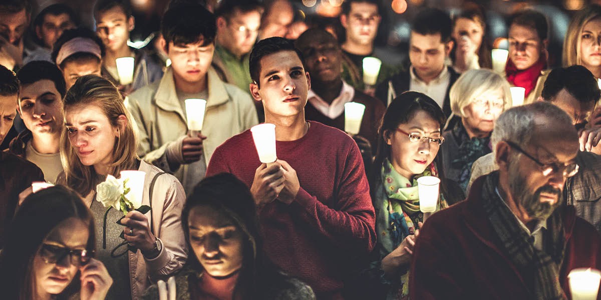 Pessoas enlutadas segurando velas