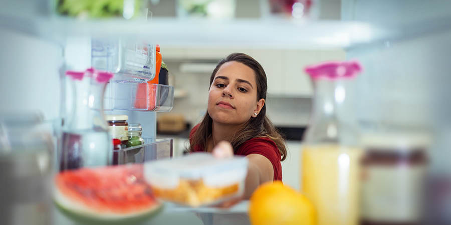 Una dona desant un recipient amb menjar a la nevera.