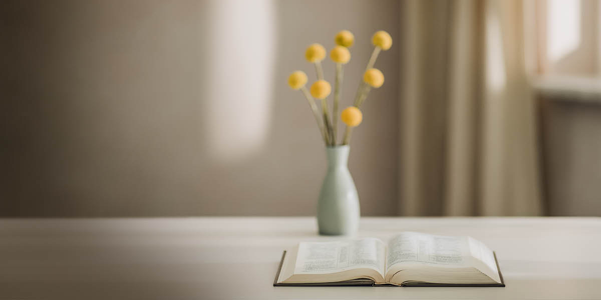 Bukas nga Bibliya duol sa flower vase.