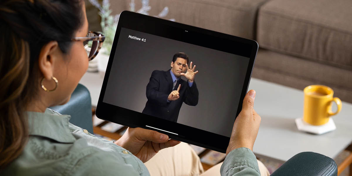 Sister nga nagtan-awg sign language nga video sa usa ka teksto diha sa iyang tablet.