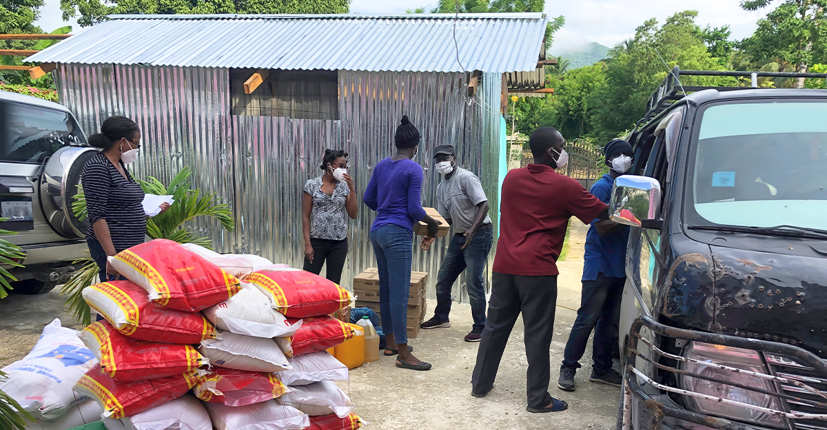 Bratři a sestry na Haiti nakládají do auta pytle s jídlem
