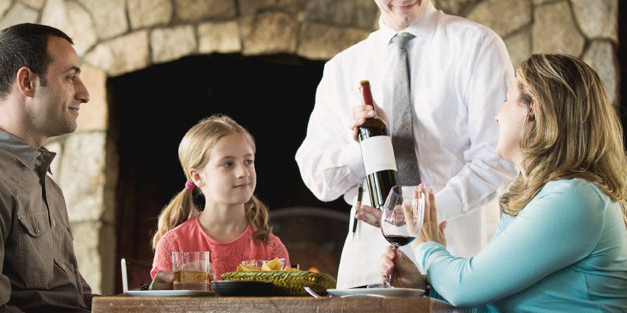 Holčička se dívá, jak maminka v restauraci odmítá další víno