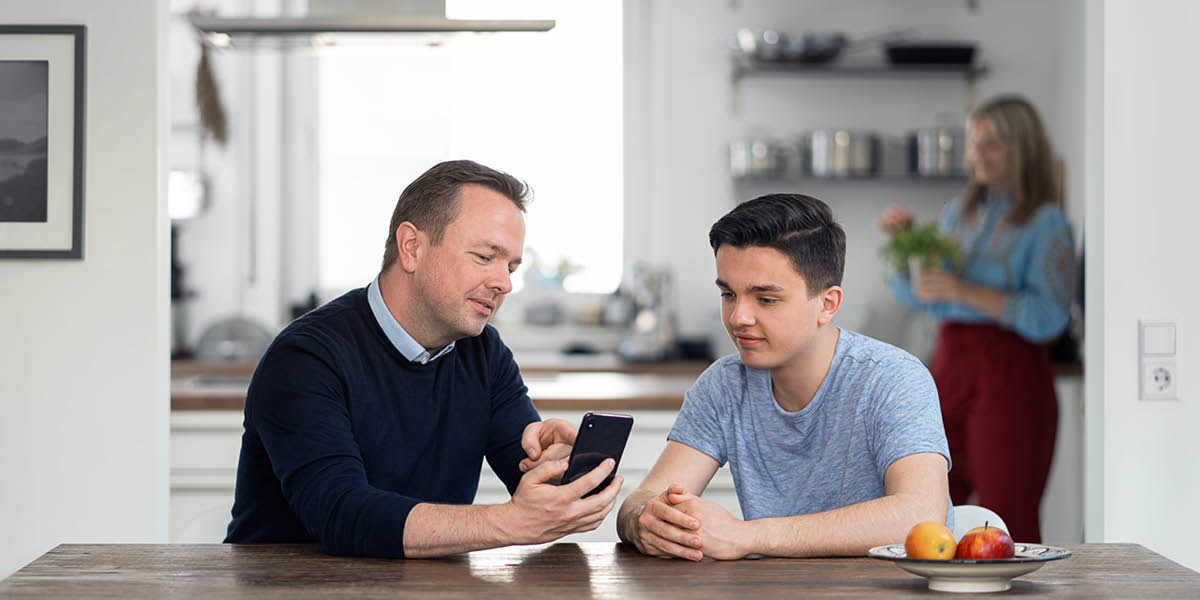 Táta učí svého syna, jak používat chytrý telefon rozumně