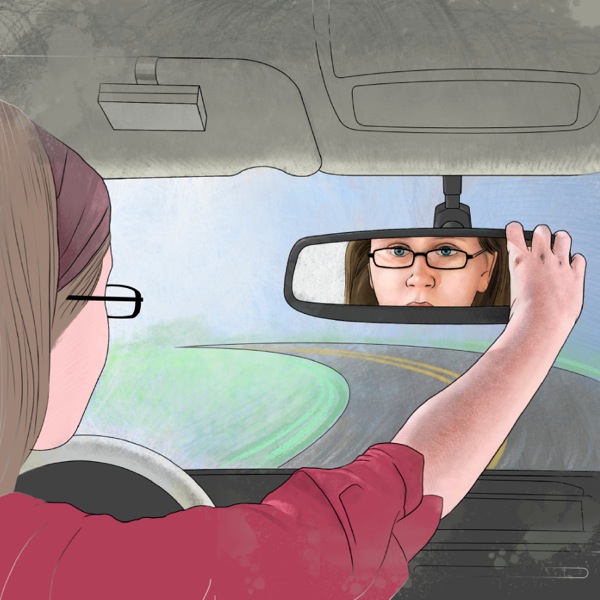 Dívka řídí auto a dívá se na sebe do zpětného zrcátka