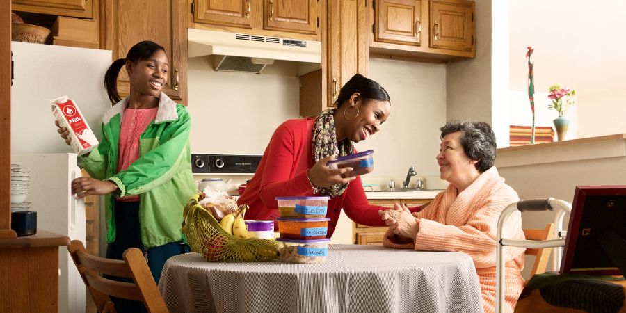 Una hermana y su hija le llevan comida a una hermana mayor