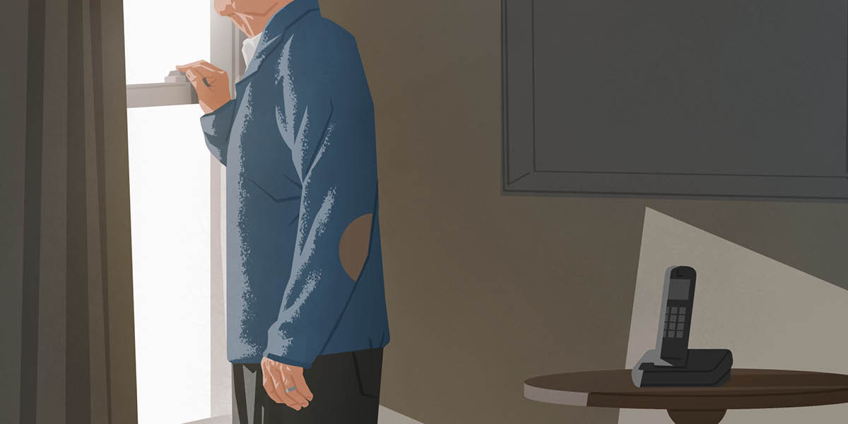 En ældre mand kigger ud ad sit vindue mens hans telefon ligger ved siden af.
