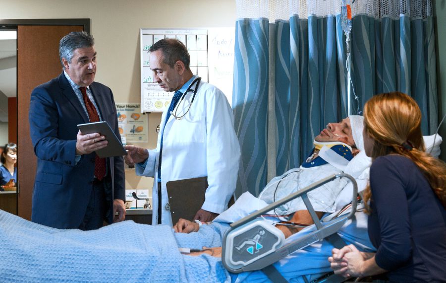 En ældste taler med en læge mens en bror ligger i en hospitalsseng