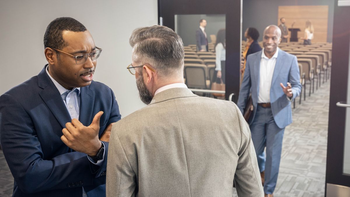 To brødre snakker sammen i rigssalen. Den ene siger noget negativt om en bror der kommer gående imod dem.