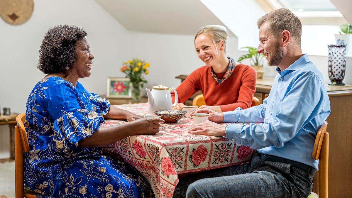 Et ungt par hygger sig med te og småkager hjemme hos en ældre søster.
