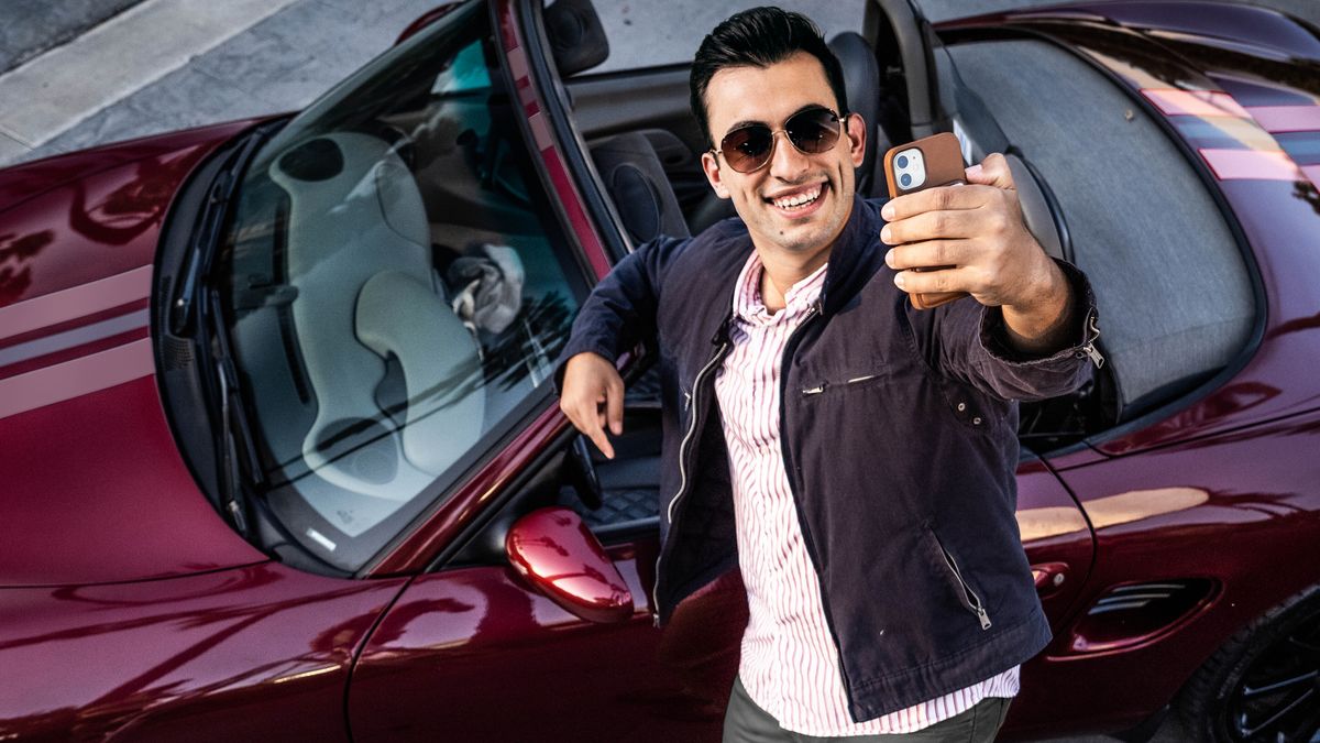 En bror tager en selfie foran sin lækre sportsvogn.