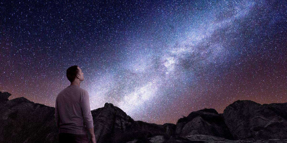 En mand der kigger op på en stjerneklar himmel