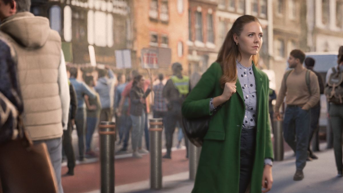 En søster forholder sig i ro mens hun går forbi en gruppe mennesker der demonstrerer på en travl gade.