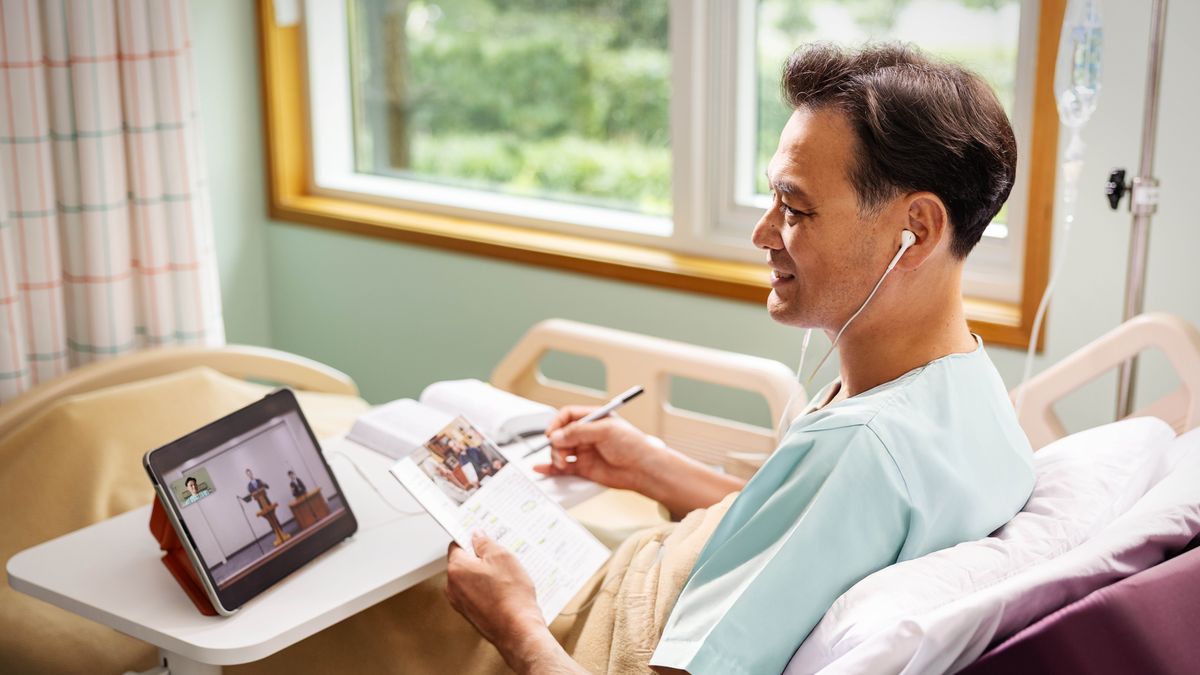 En bror der er på hospitalet, overværer Vagttårnsstudiet via videokonference. Han følger med i sit eget Vagttårn og i sin egen bibel.