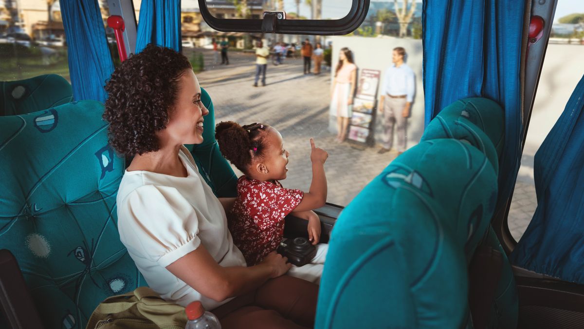 En mor og datter sidder i en bus og glæder sig over at se deres brødre og søstre der står ved standen.
