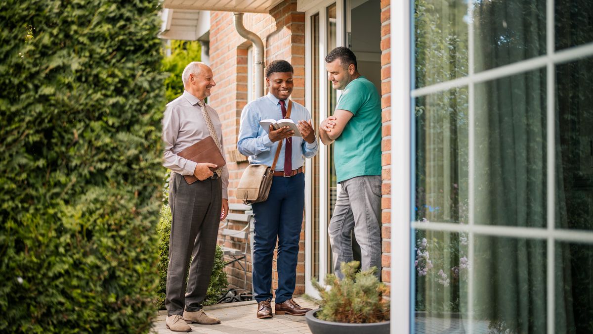 En af de nydøbte brødre fra det tidligere billede viser et bibelvers til en mand han møder fra hus til hus.