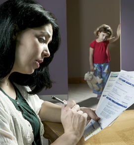 Eine Mutter schaut besorgt auf die vielen Rechnungen