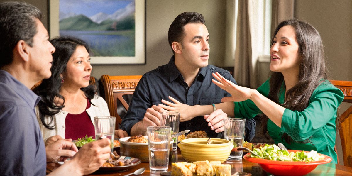 Zwei Ehepaare beim Abendessen; eine Frau fällt ihrem Mann ins Wort