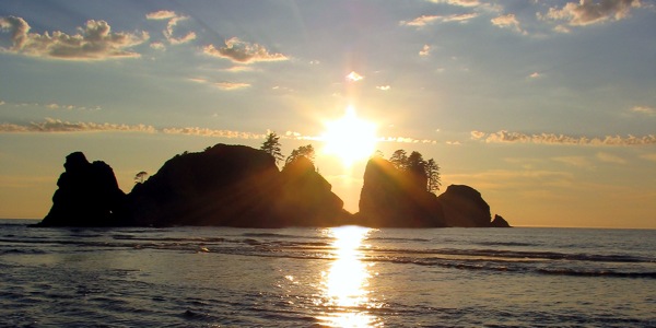 Ein Sonnenuntergang über einer Insel spiegelt sich im Ozean