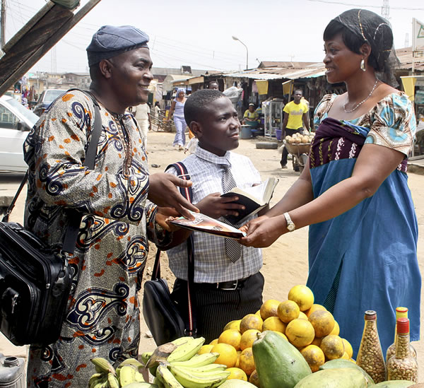 Zwei Zeugen Jehovas beim Predigen auf einem afrikanischen Markt