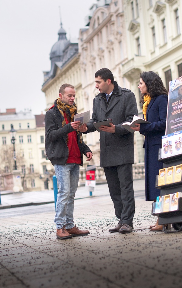 In einer Innenstadt: Zeugen Jehovas sprechen mit einem Mann über die Bibel