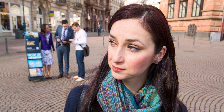 Eine Frau beobachtet zwei Zeugen Jehovas, die mit einem Literatur-Trolley unterwegs sind