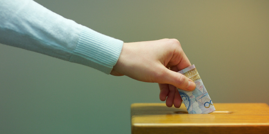 Geld wird in einen Spendenkasten geworfen