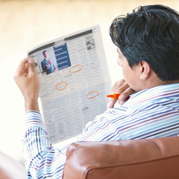A man looking in a newspaper for potential work