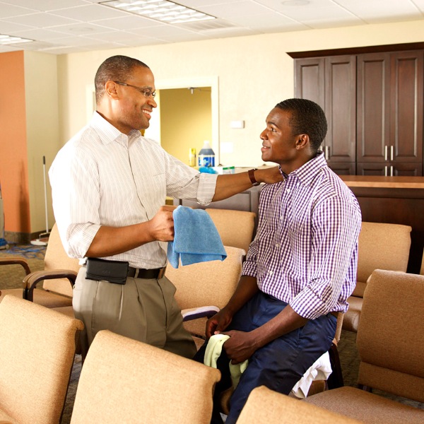 At the Kingdom Hall, an elder explains to a young brother why a task needs to be done