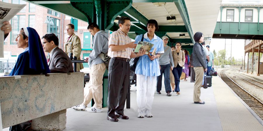 Un hermano predicándole a una mujer en una estación de tren llena de gente.
