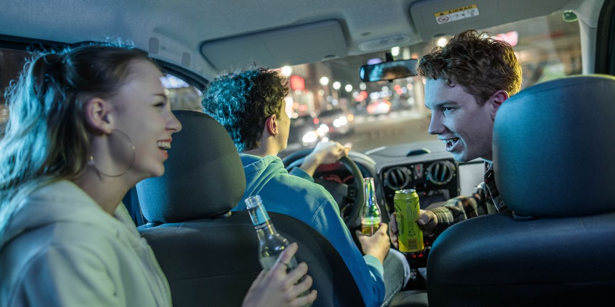 Un joven conduce un auto mientras él y sus amigos toman bebidas alcohólicas.