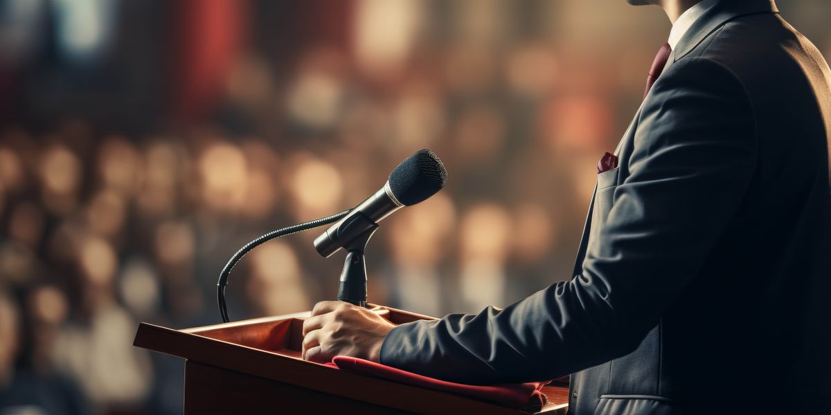 Un político da un discurso ante una multitud de personas.