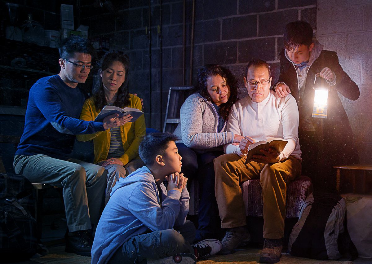 Algunas familias estudiando la Biblia juntas durante la gran tribulación en un sótano