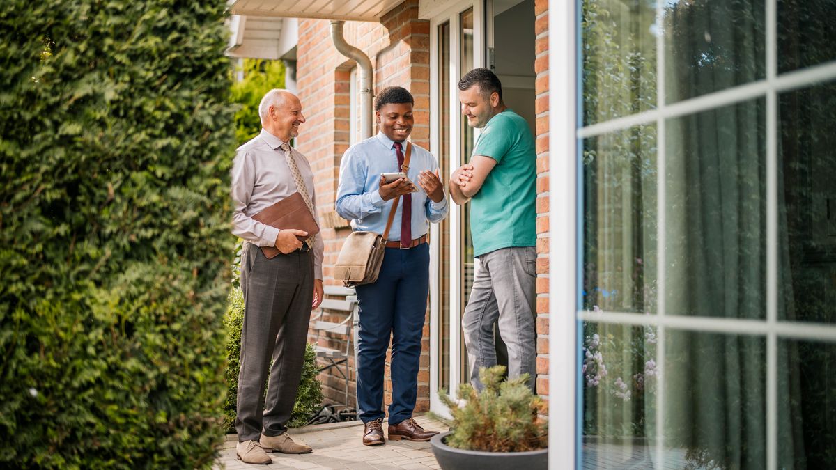 Un hermano recién bautizado de la imagen anterior predicando de casa en casa y leyéndole un texto bíblico a un hombre.