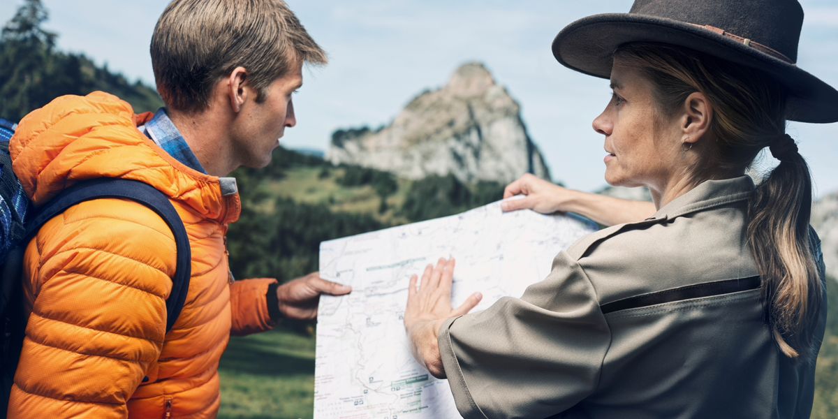 El hombre joven de la imagen anterior ahora está en el campo. Una guarda forestal le muestra en un mapa qué ruta tomar para llegar a su destino, que es la cima de una montaña.
