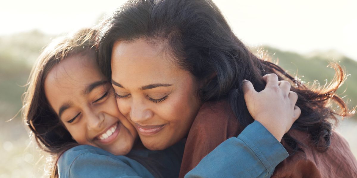 A mother embracing her daughter on a sunny day.